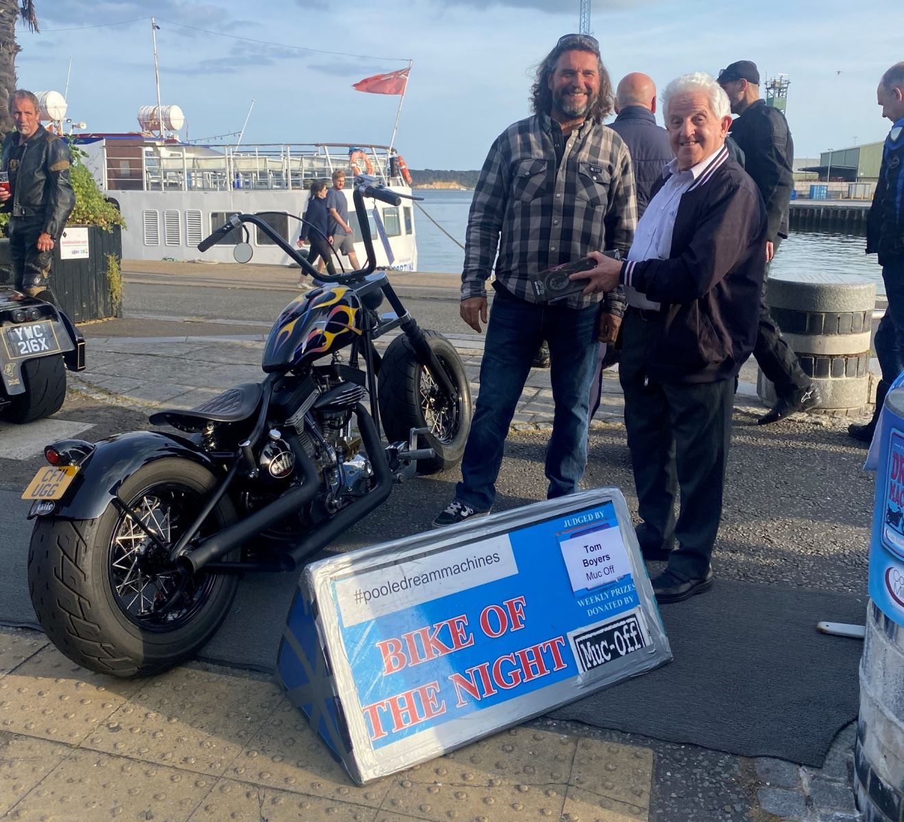 Two men smiling at camera after winning bike of the night in Poole